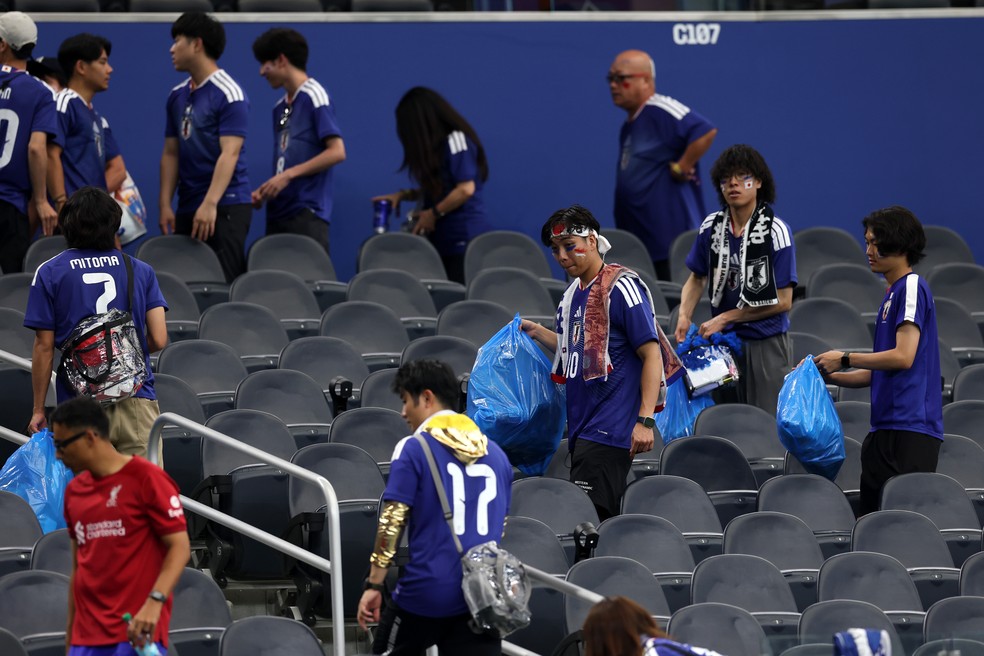 Torcedores japoneses recolhendo o lixo do Dallas Stadium após o empate entre Japão e Holanda, por 2 a 2, na primeira rodada da Copa do Mundo, em 14 de junho de 2026 — Foto: Getty Images