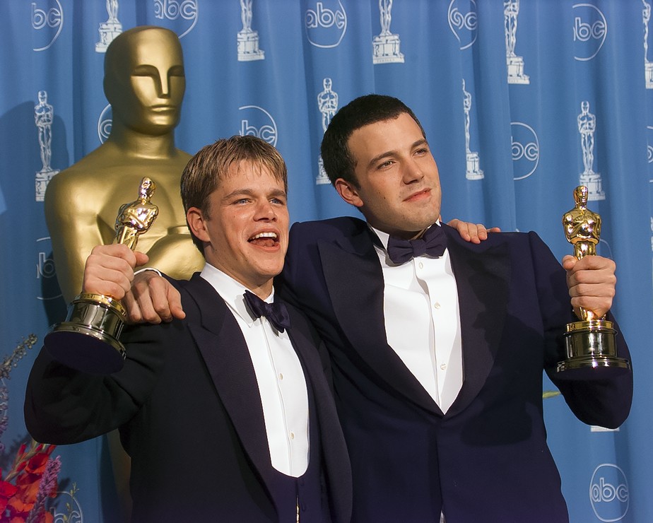 Matt Damon e Ben Affleck com as estatuetas do Oscar vencidas por eles em 1998, na categoria de melhor roteiro original, por Gênio Indomável (1997)