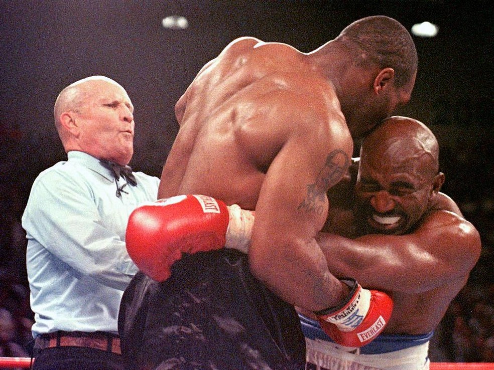 O juiz tentando separar Mike Tyson de Evander Holyfield na luta de junho de 1997, após Tyson morder a orelha do rival — Foto: Getty Images