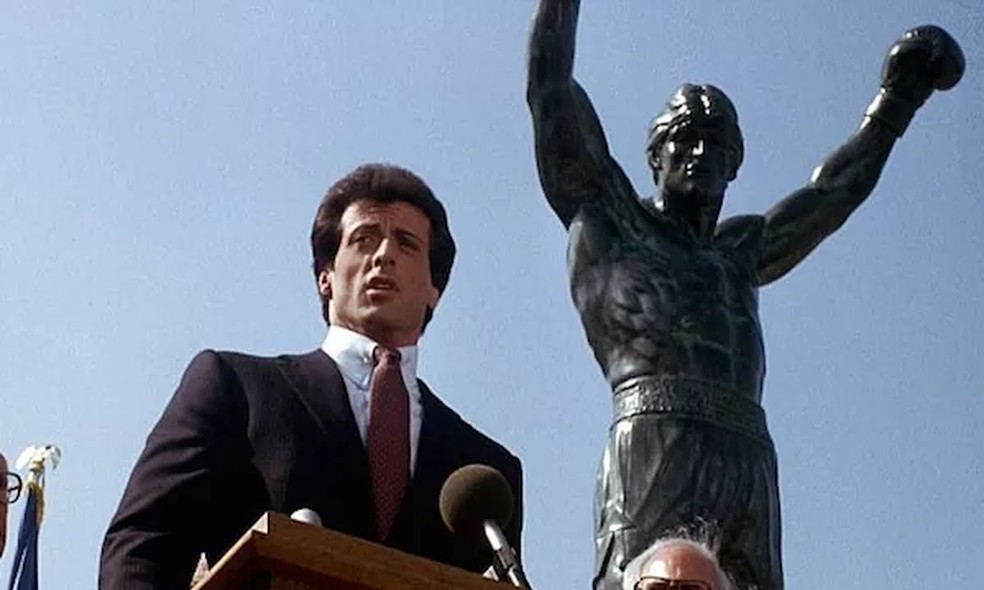 O ator Sylvester Stallone em cena de Rocky III (1982) na qual aparece em frente à estátua vendida para Adele junto com mansão em Miami — Foto: Reprodução