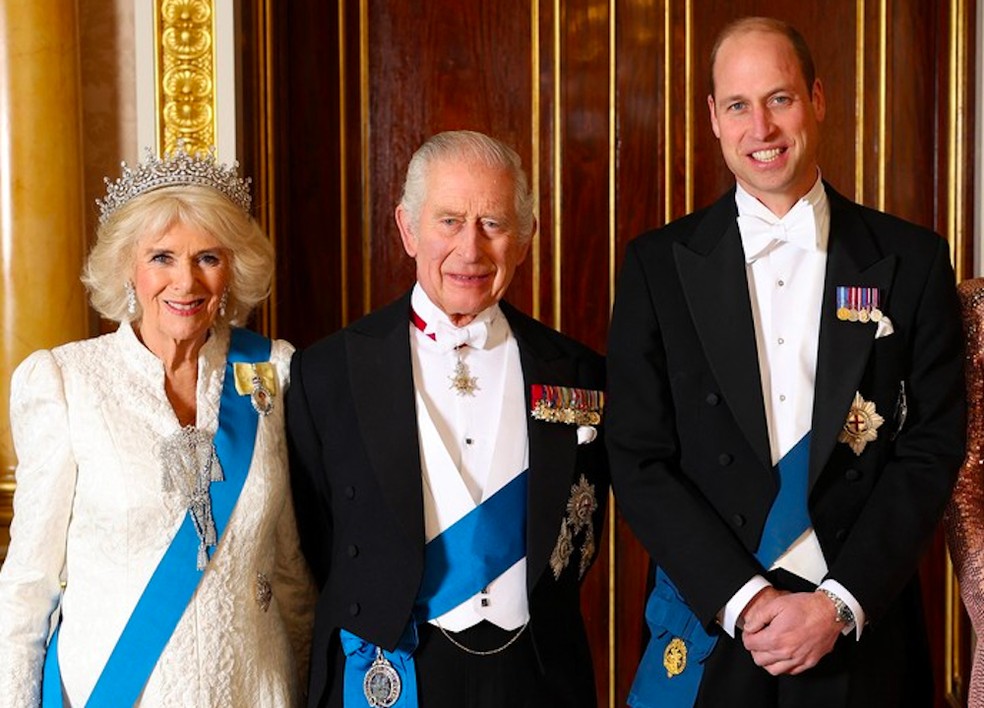 O Rei Charles III ladeado pela esposa, Rainha Consorte Camilla, e o filho, Príncipe William — Foto: Getty Images