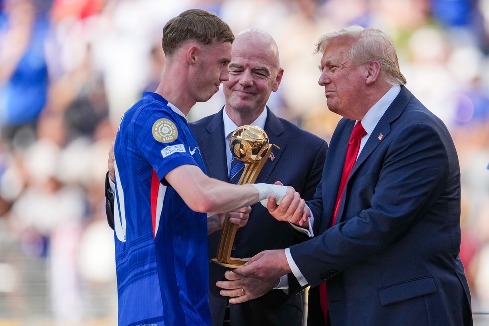 Cole Palmer recebendo das mãos de Donald Trump o troféu de melhor jogador da Copa de Mundo de Clubes da FIFA, sob os olhares do cartola Gianni Infantino — Foto: Getty Images