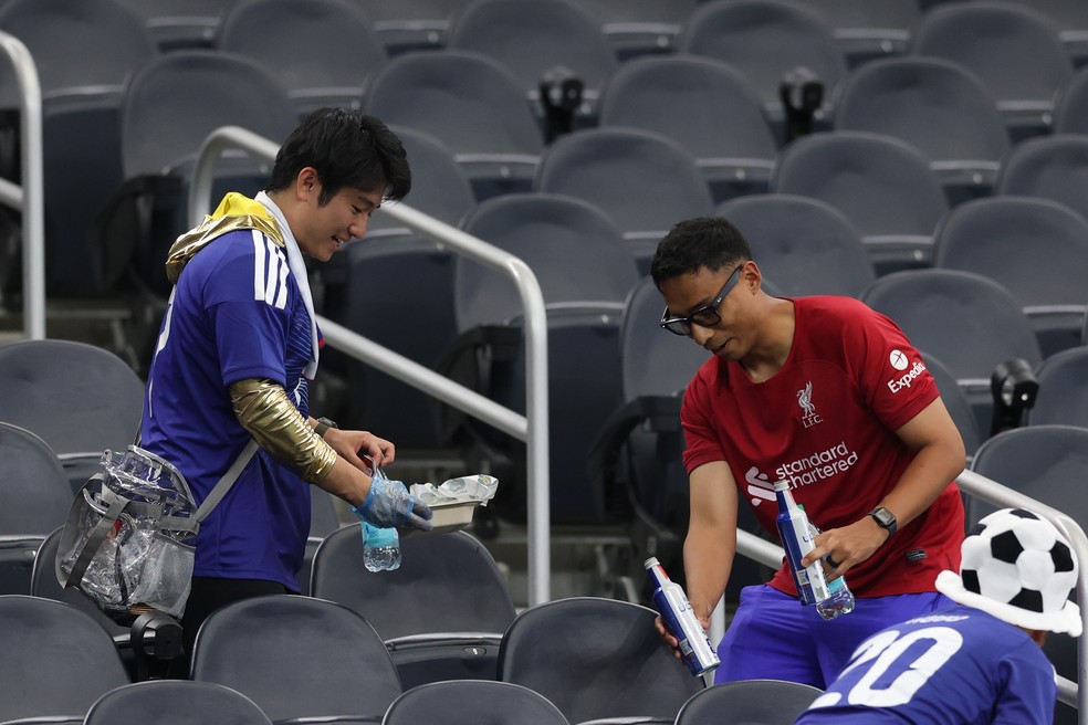 Torcedores japoneses recolhendo o lixo do Dallas Stadium após o empate entre Japão e Holanda, por 2 a 2, na primeira rodada da Copa do Mundo, em 14 de junho de 2026 — Foto: Getty Images