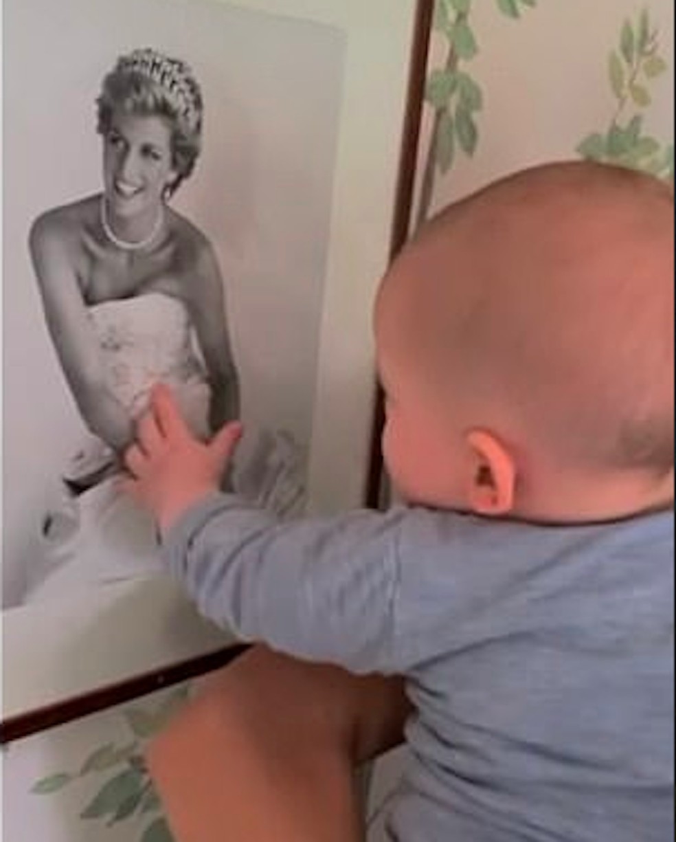 O filho mais velho do Príncipe Harry e da atriz e Duquesa Meghan Markle, Archie, em foto antiga interagindo com retrato da avó Princesa Diana (1961-1997) — Foto: Reprodução