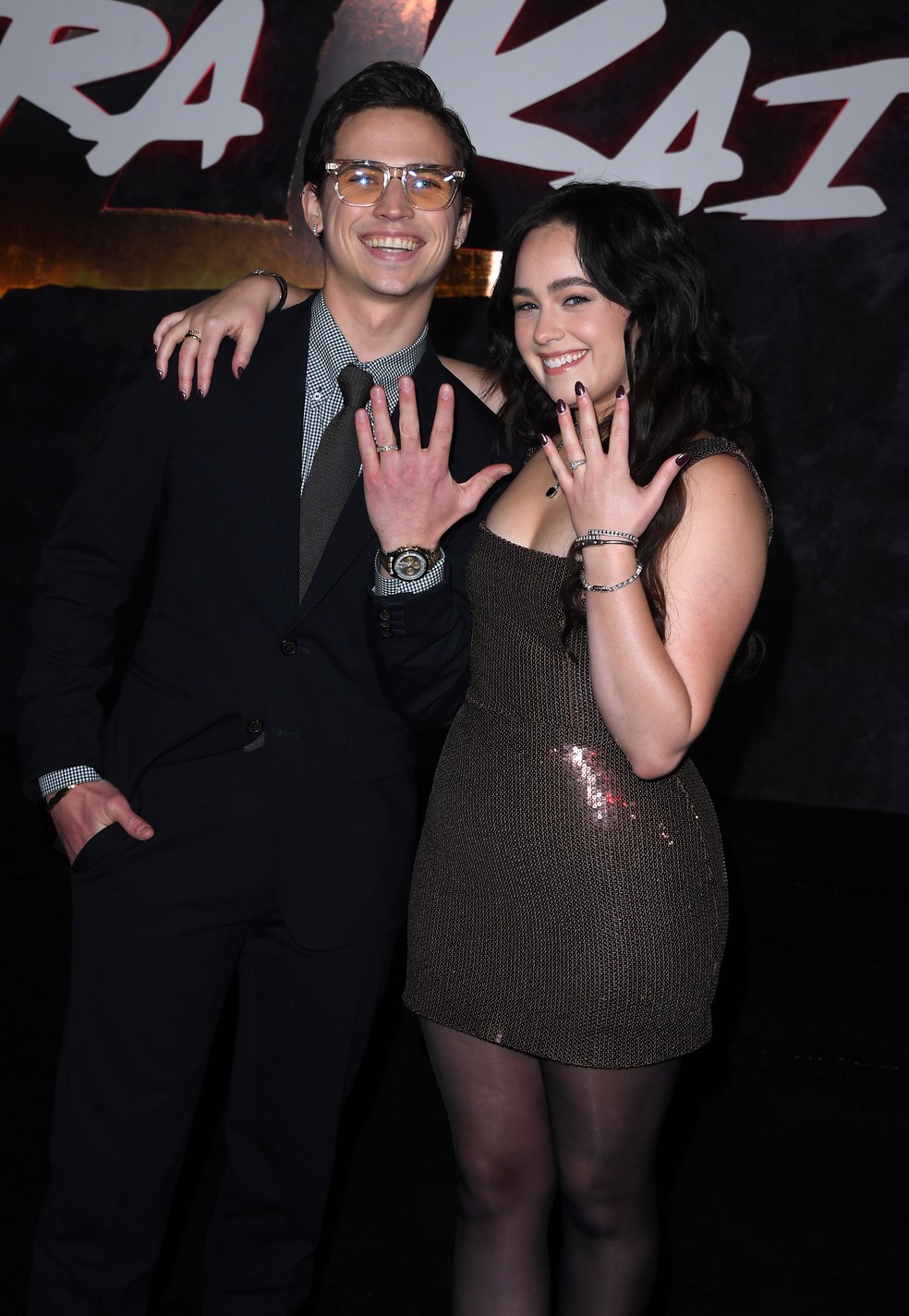 Tanner Buchanan e Mary Mouser mostrando suas alianças de noivado no evento de lançamento da última temporada de Cobra Kai — Foto: Getty Images