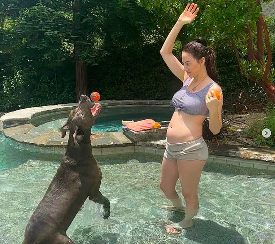 A atriz Whitney Cummings revelou a gravidez em álbum com fotos brincando com cachorro na piscina
